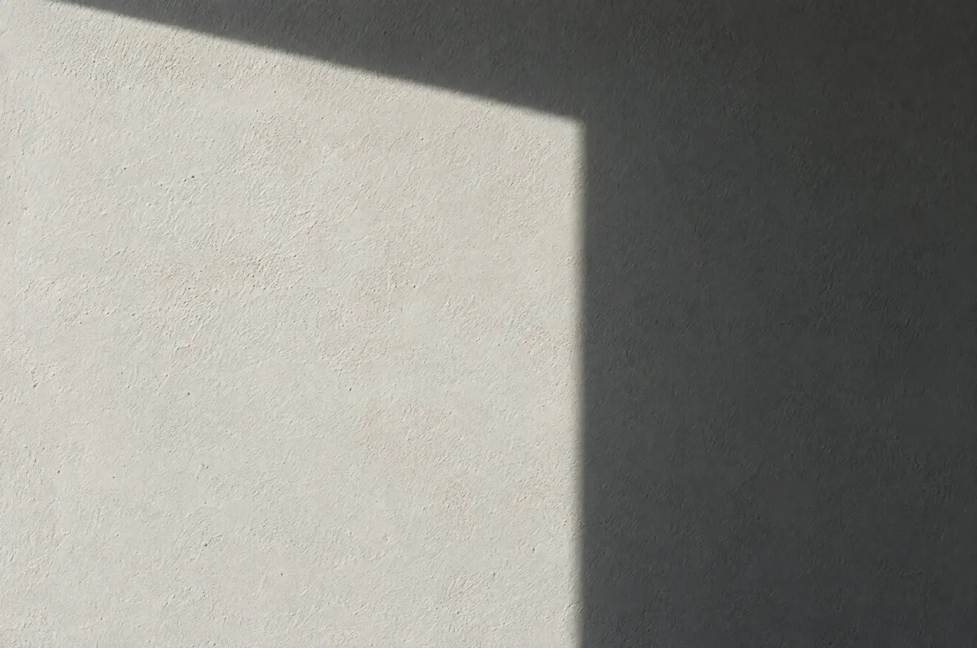 A crisp window shadow on pale mineral plaster