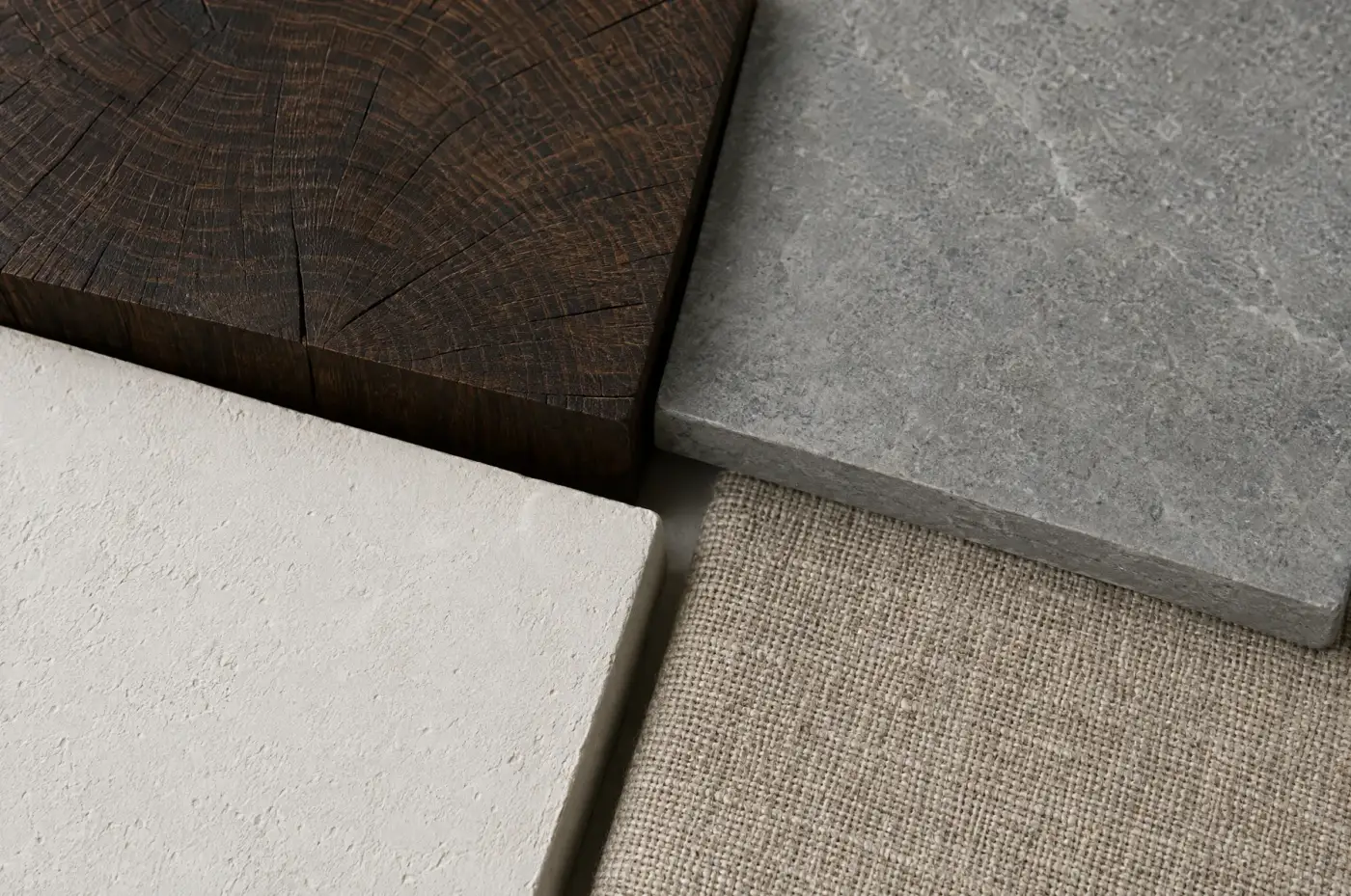 Timber end grain, stone, plaster, and woven linen arranged in a material study